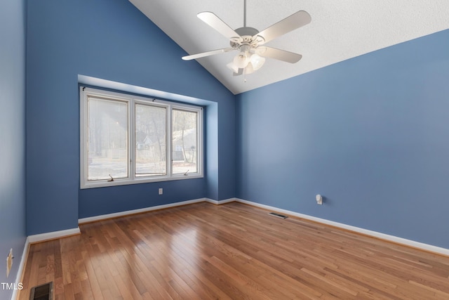 empty room featuring visible vents, vaulted ceiling, baseboards, and wood finished floors