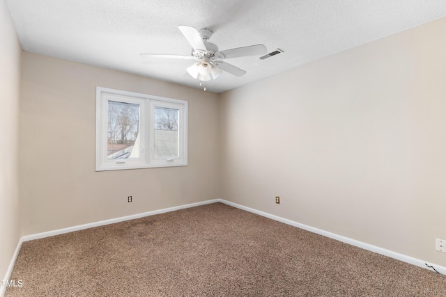 carpeted spare room with a textured ceiling, visible vents, a ceiling fan, and baseboards