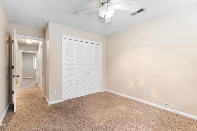 unfurnished bedroom with baseboards, visible vents, a ceiling fan, carpet, and a closet