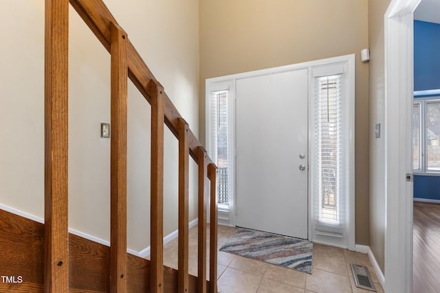 foyer featuring light tile patterned floors, stairs, visible vents, and baseboards