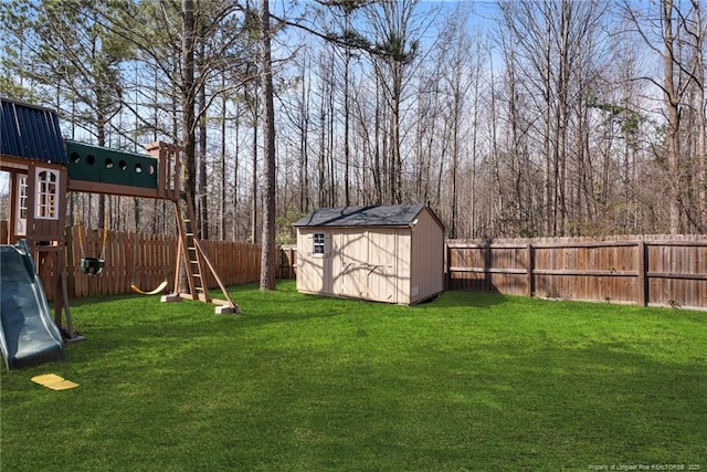 view of yard with an outbuilding, a playground, a fenced backyard, and a shed