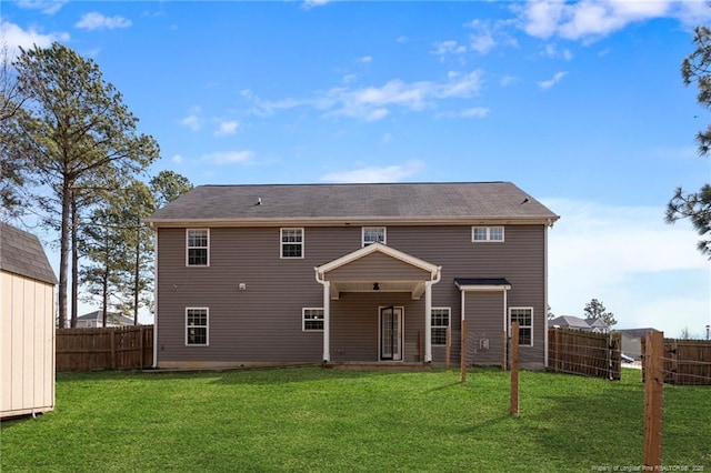 rear view of house featuring a yard and a fenced backyard