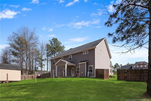 rear view of house featuring a lawn, an outdoor structure, and fence