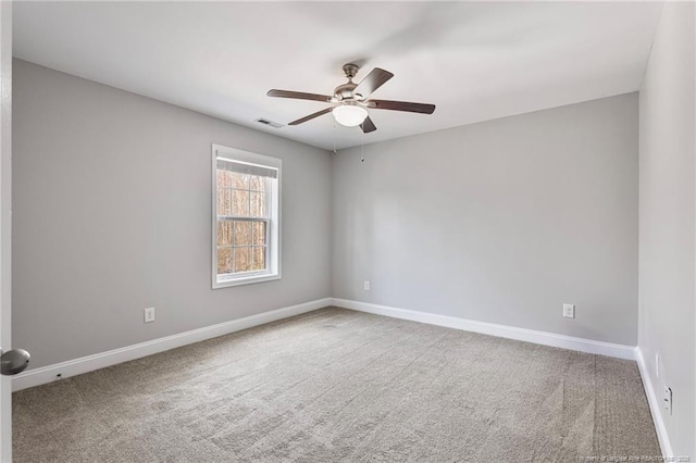 carpeted spare room with visible vents, baseboards, and ceiling fan