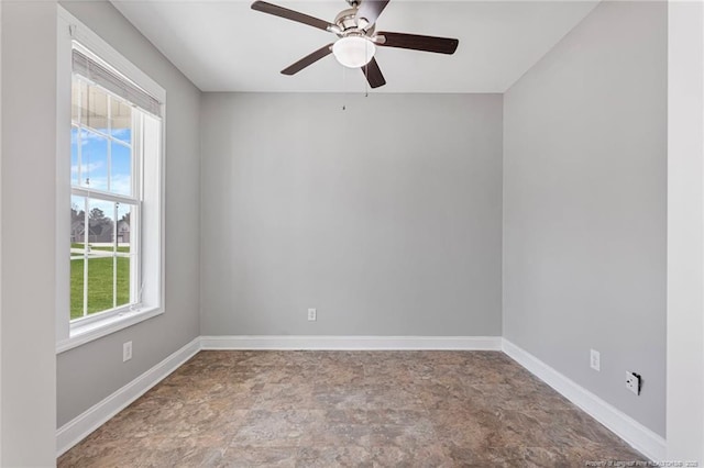 spare room with a ceiling fan and baseboards