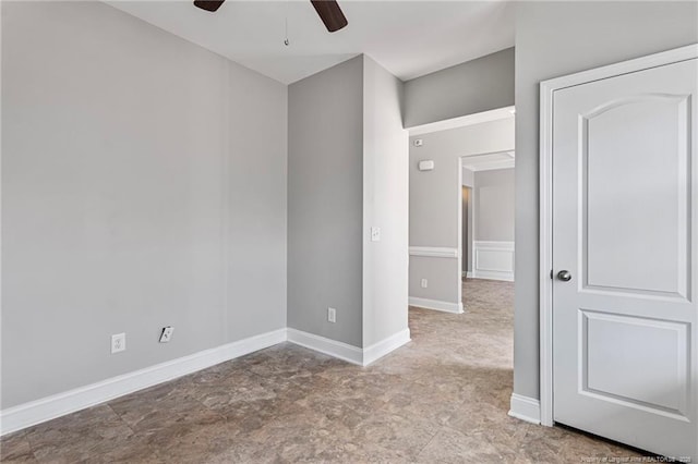 empty room with a ceiling fan and baseboards