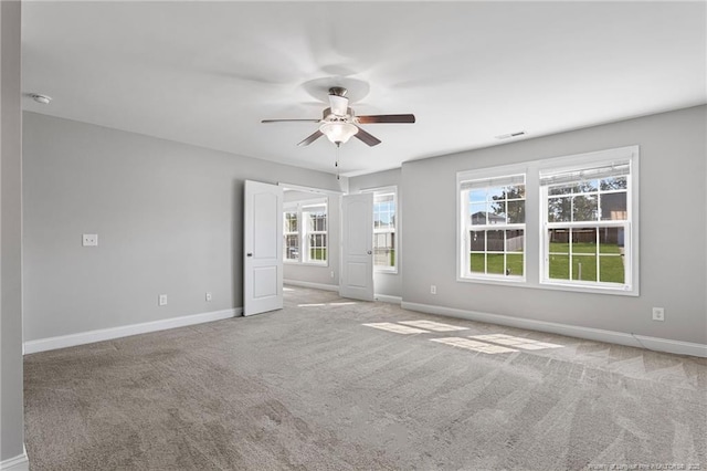 carpeted empty room with ceiling fan, visible vents, and baseboards