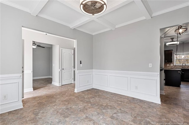 spare room with coffered ceiling, a wainscoted wall, ceiling fan, beamed ceiling, and a decorative wall