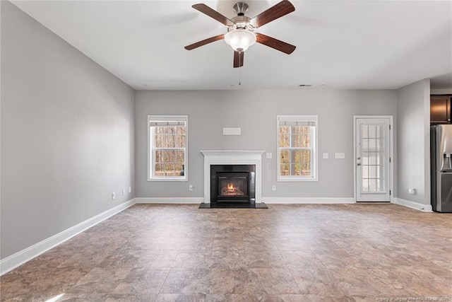 unfurnished living room with ceiling fan, visible vents, baseboards, and a glass covered fireplace