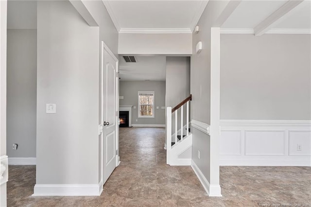 interior space featuring a wainscoted wall, crown molding, visible vents, a decorative wall, and stairs