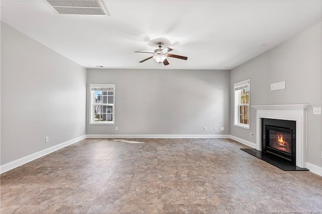 unfurnished living room featuring a glass covered fireplace, visible vents, ceiling fan, and baseboards