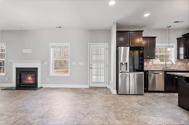 kitchen featuring dark brown cabinetry, baseboards, visible vents, decorative backsplash, and stainless steel appliances