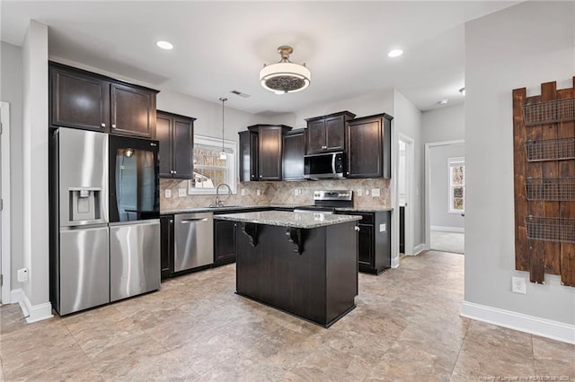 kitchen with light stone countertops, tasteful backsplash, stainless steel appliances, and a sink