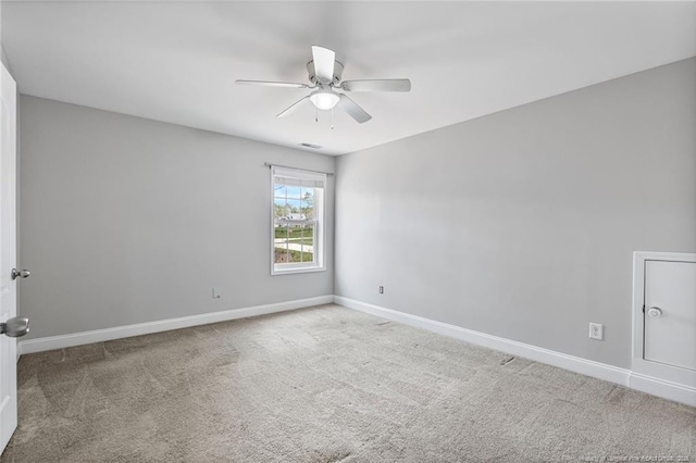 carpeted spare room with ceiling fan and baseboards