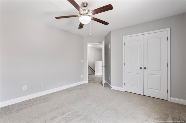 unfurnished bedroom featuring carpet floors, a closet, baseboards, and a ceiling fan