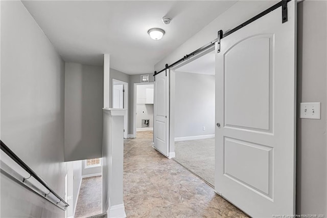 hallway with a barn door and baseboards