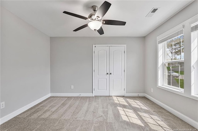 unfurnished bedroom with carpet, a closet, visible vents, a ceiling fan, and baseboards