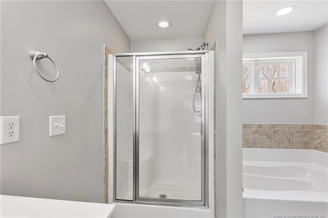 bathroom with a shower stall, a bath, and recessed lighting