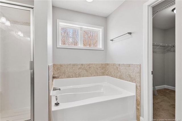 bathroom featuring a garden tub, a spacious closet, and a shower stall