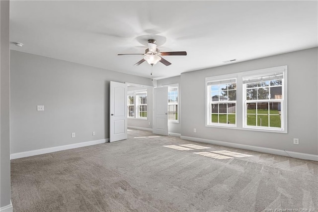 carpeted empty room with baseboards, visible vents, and a ceiling fan