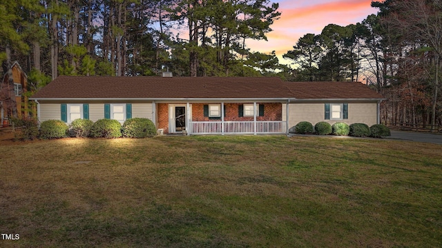 ranch-style house featuring a yard, brick siding, and a chimney