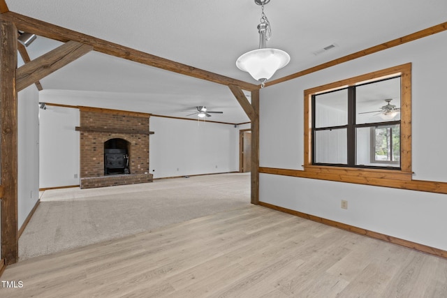 unfurnished living room featuring baseboards, visible vents, beamed ceiling, and wood finished floors