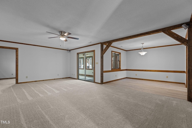 empty room featuring crown molding, light colored carpet, ceiling fan, a textured ceiling, and baseboards