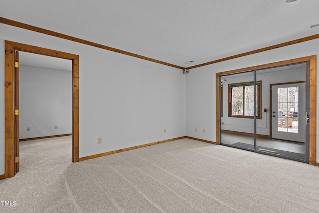 carpeted empty room with ornamental molding, visible vents, a textured ceiling, and baseboards