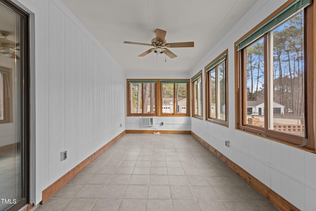 unfurnished sunroom featuring a wall mounted AC, a wealth of natural light, and a ceiling fan