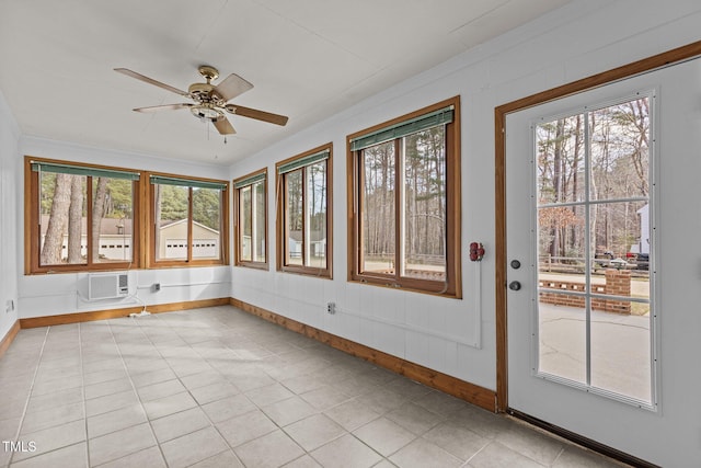 unfurnished sunroom featuring ceiling fan, a wall unit AC, and a healthy amount of sunlight