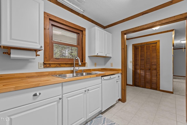 kitchen featuring a textured ceiling, white dishwasher, butcher block counters, a sink, and white cabinets