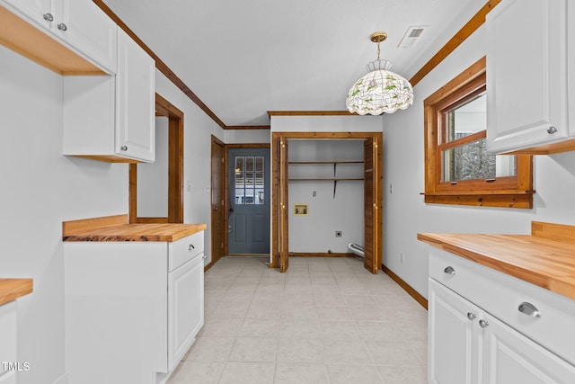 kitchen featuring visible vents, white cabinetry, wooden counters, decorative light fixtures, and crown molding