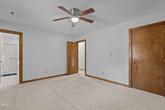 unfurnished bedroom with visible vents, carpet flooring, a textured ceiling, ensuite bath, and baseboards