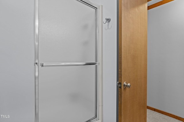 bathroom featuring a shower with door and baseboards