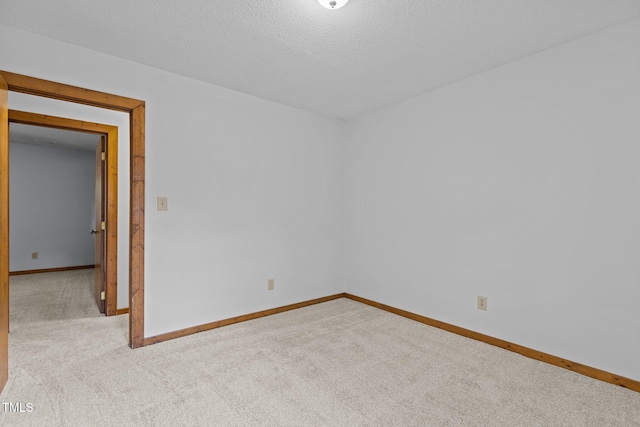 carpeted spare room featuring baseboards and a textured ceiling