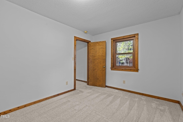 spare room featuring carpet floors, a textured ceiling, and baseboards