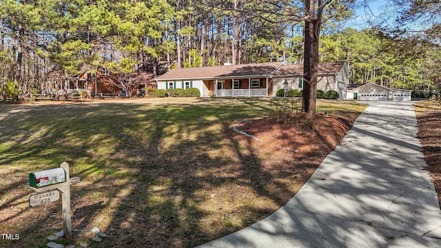 view of front of property featuring a detached garage, a porch, an outbuilding, and a front yard