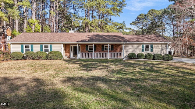 single story home featuring covered porch, brick siding, a chimney, and a front yard