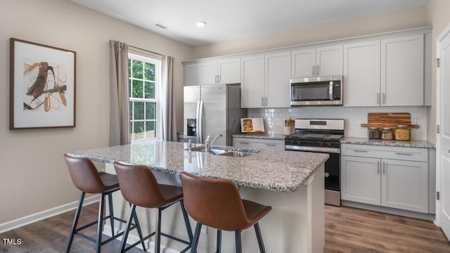 kitchen featuring appliances with stainless steel finishes, dark wood-style flooring, a sink, and decorative backsplash