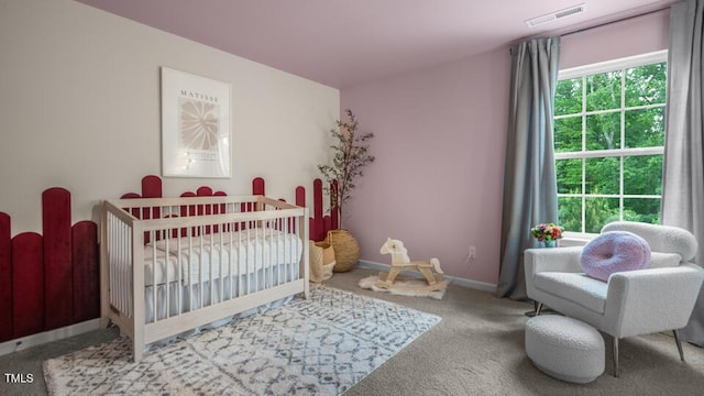 carpeted bedroom featuring a nursery area, visible vents, and baseboards