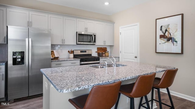 kitchen featuring appliances with stainless steel finishes, dark wood-type flooring, a sink, and tasteful backsplash