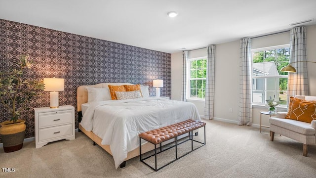 bedroom with visible vents, an accent wall, light carpet, baseboards, and wallpapered walls