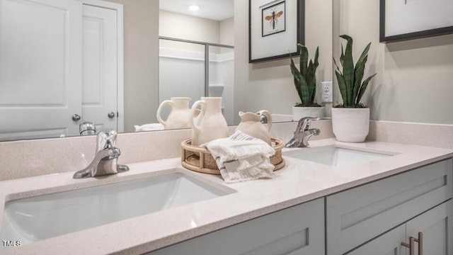 bathroom with a sink, a shower stall, and double vanity