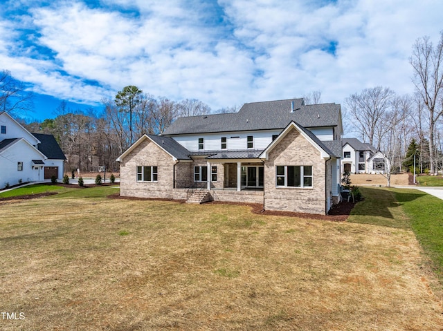 back of house featuring brick siding, a shingled roof, and a yard