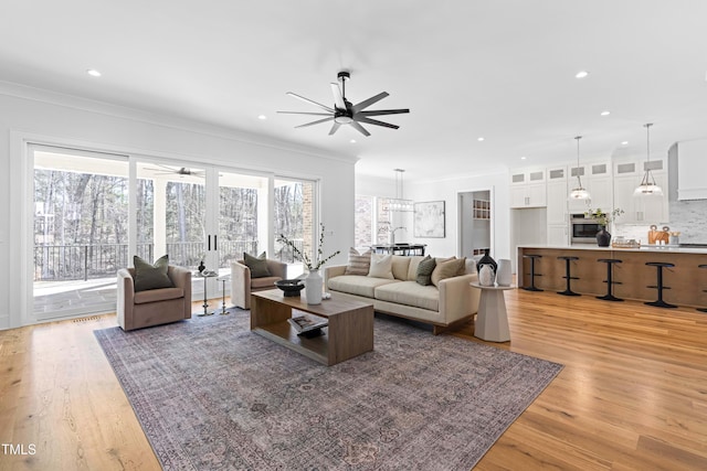 living area with light wood-style flooring, ornamental molding, a ceiling fan, and recessed lighting