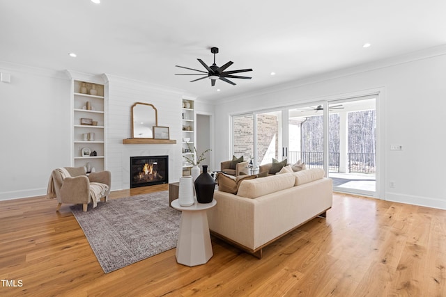 living room with ornamental molding, baseboards, and light wood finished floors