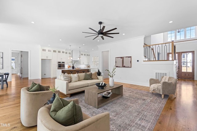 living area featuring baseboards, ornamental molding, light wood-type flooring, and recessed lighting