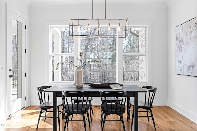 dining space with a chandelier, ornamental molding, wood finished floors, and baseboards