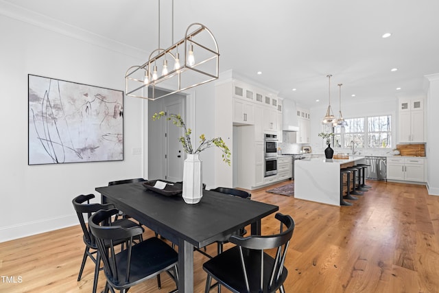 dining space featuring baseboards, ornamental molding, light wood-style flooring, and recessed lighting