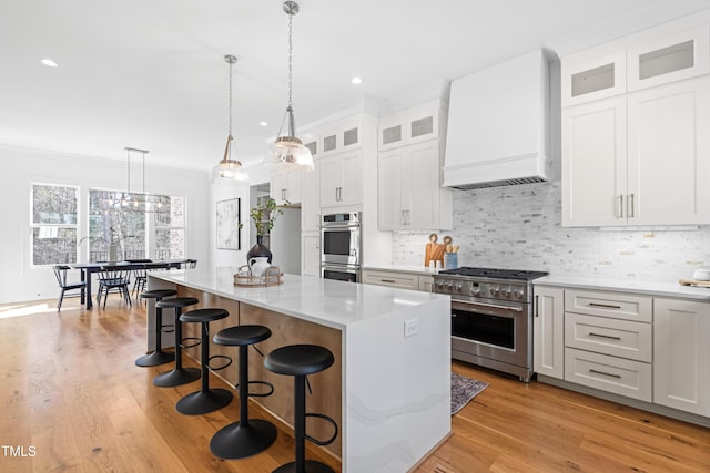 kitchen with tasteful backsplash, custom range hood, appliances with stainless steel finishes, a center island, and a kitchen bar